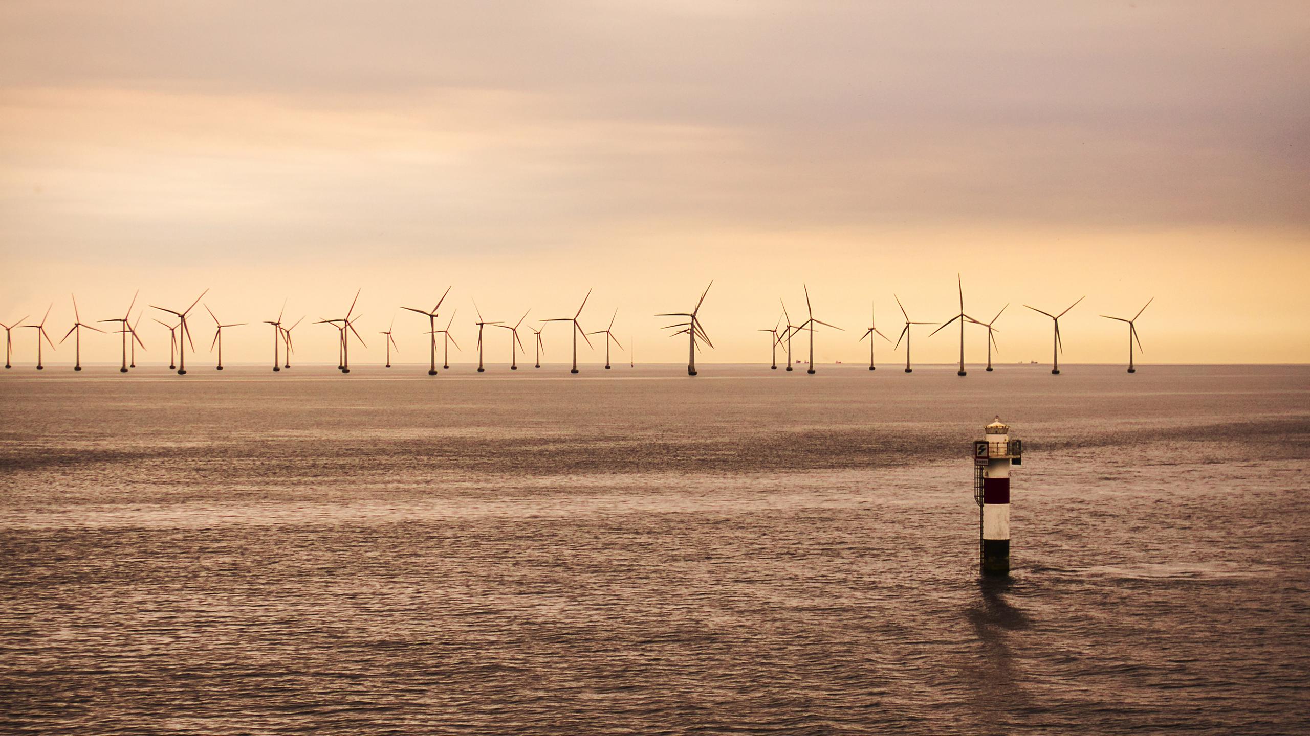 Offshore wind farm at sunset with a navigation marker in the foreground