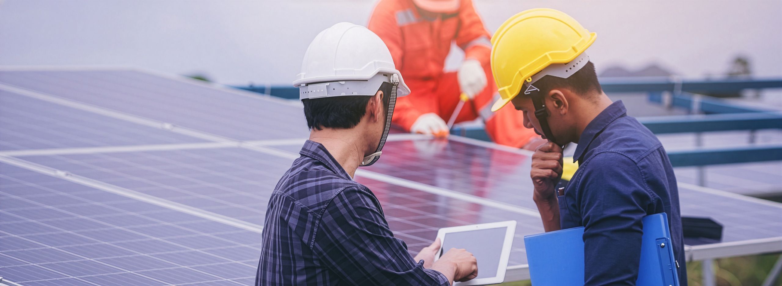 Technicians inspecting solar panels with a tablet