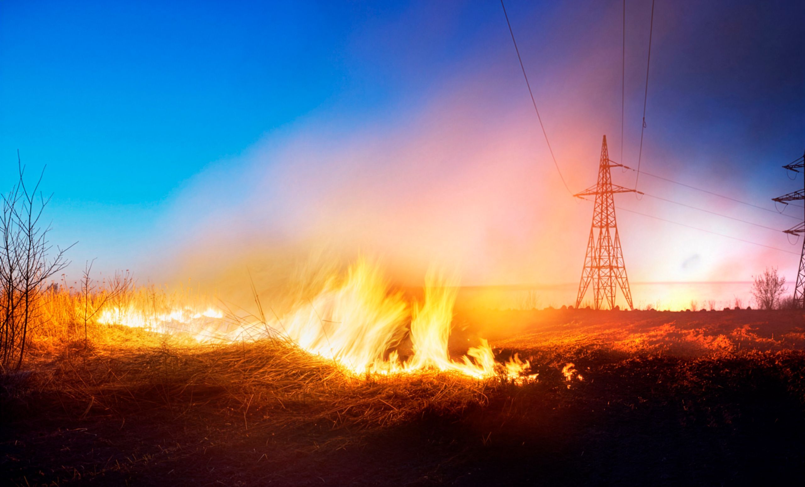 Grass wildfire burning near high-voltage transmission towers