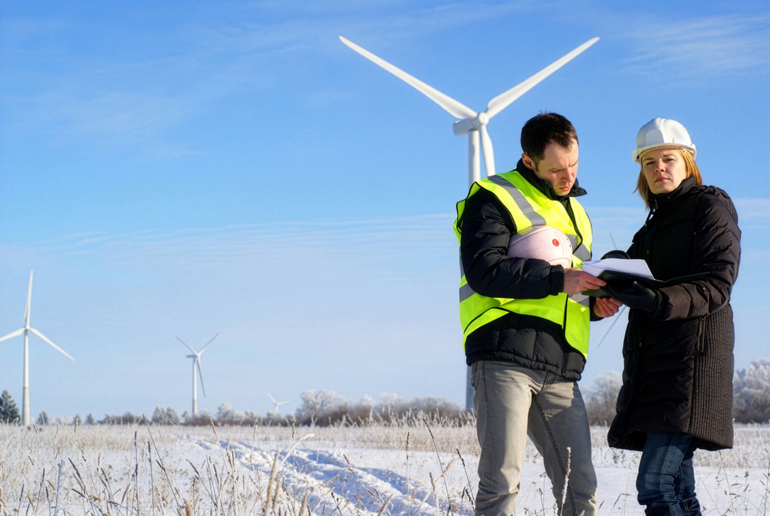 Wind technicians reviewing plans at a snowy wind farm