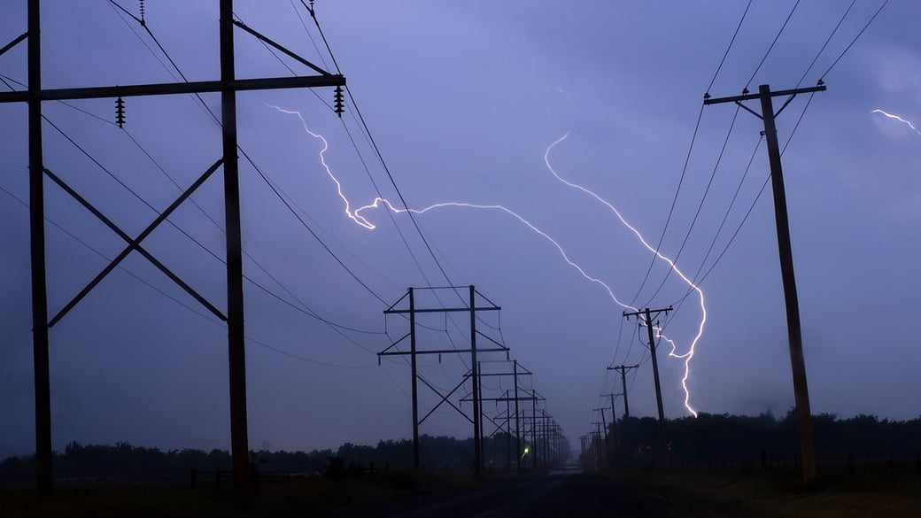 Lightning over utility lines at night
